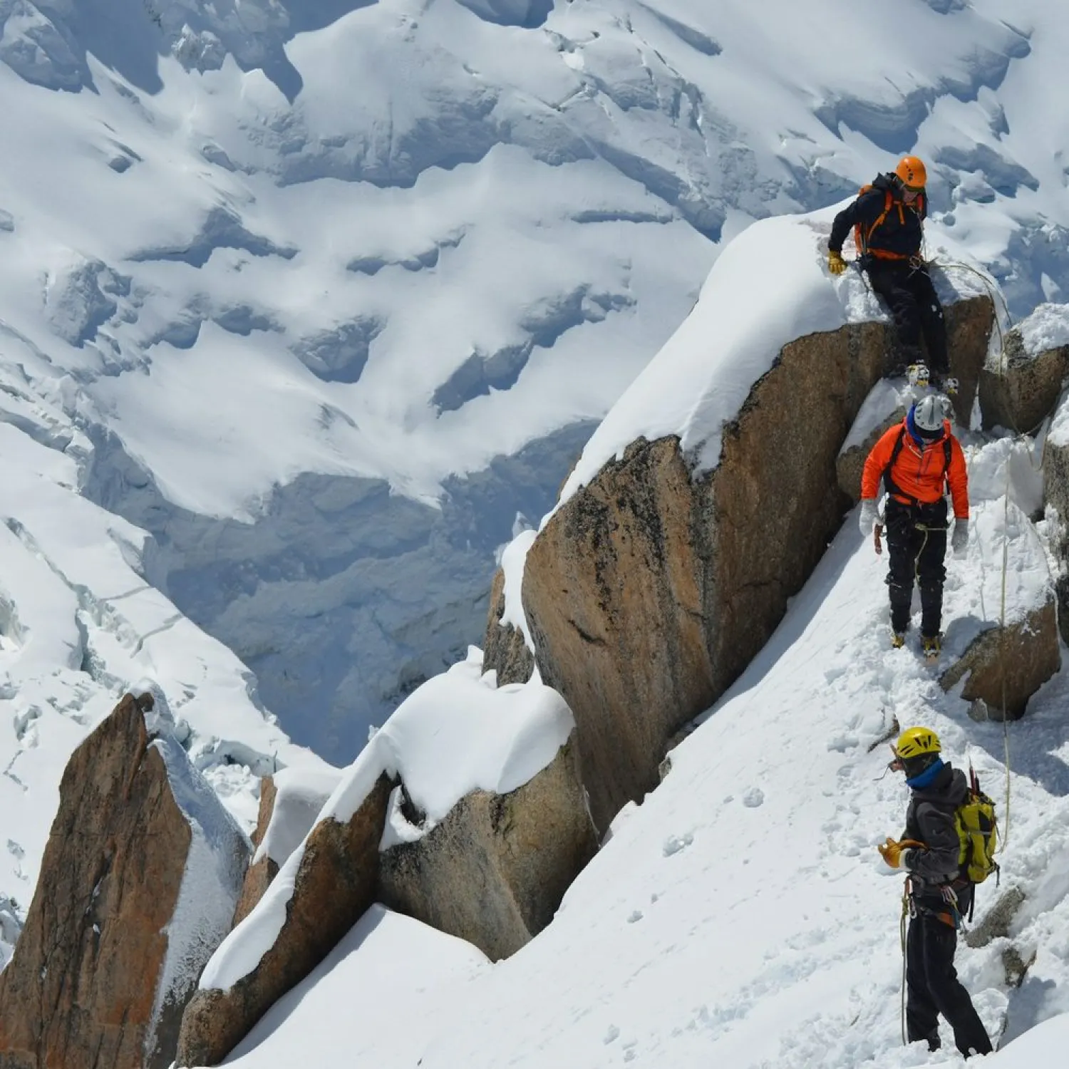 A roped team climbing a snowy rock ridge