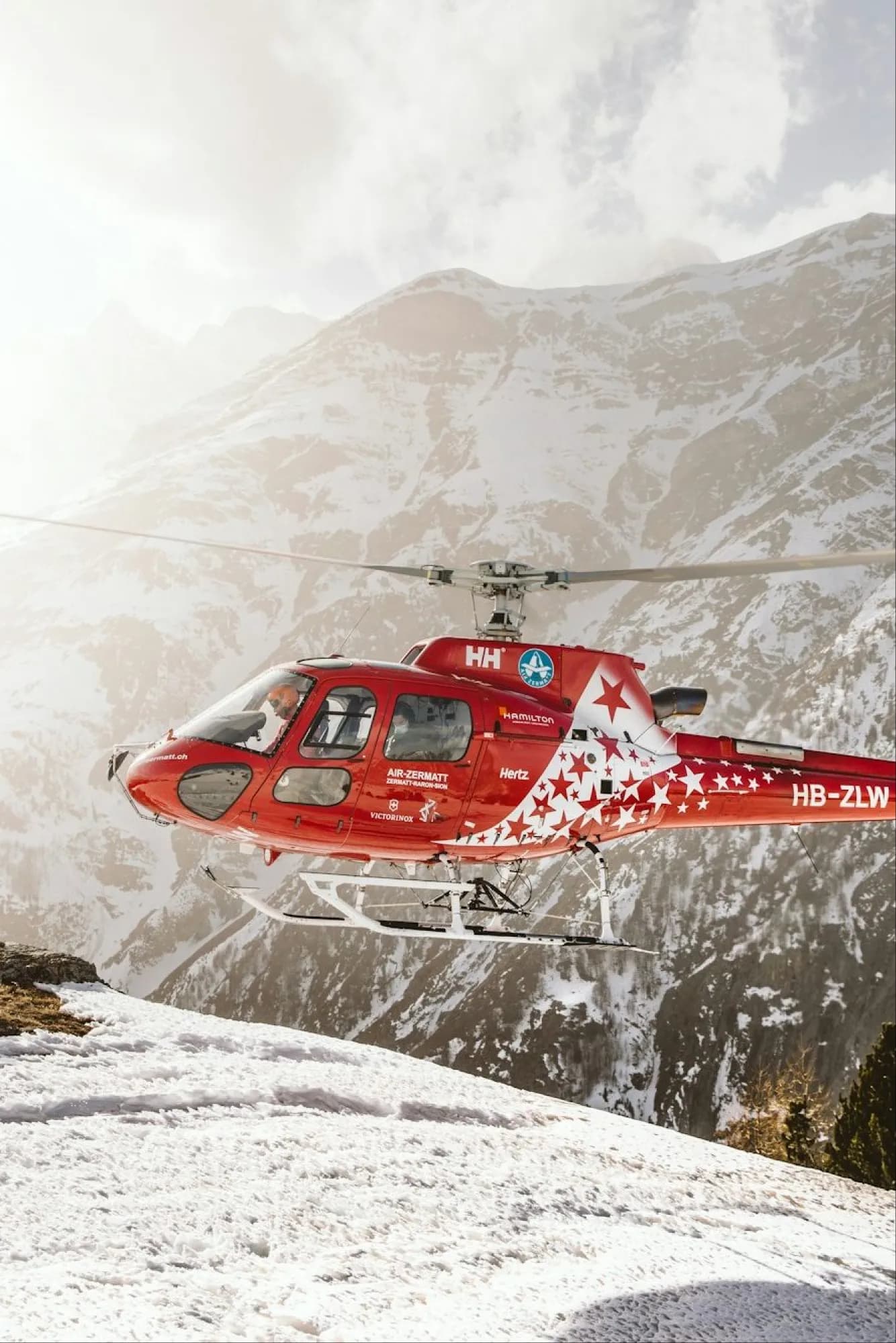 A rescue helicopter landing on a snowy slope