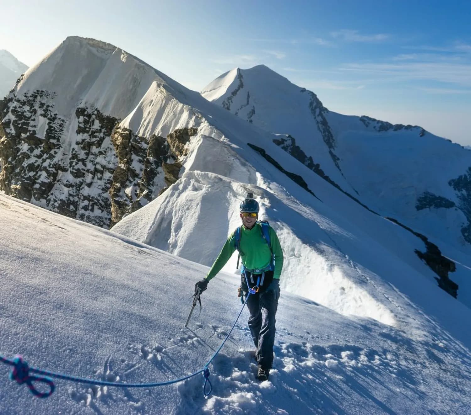 A roped climber moving along a snowy ridge