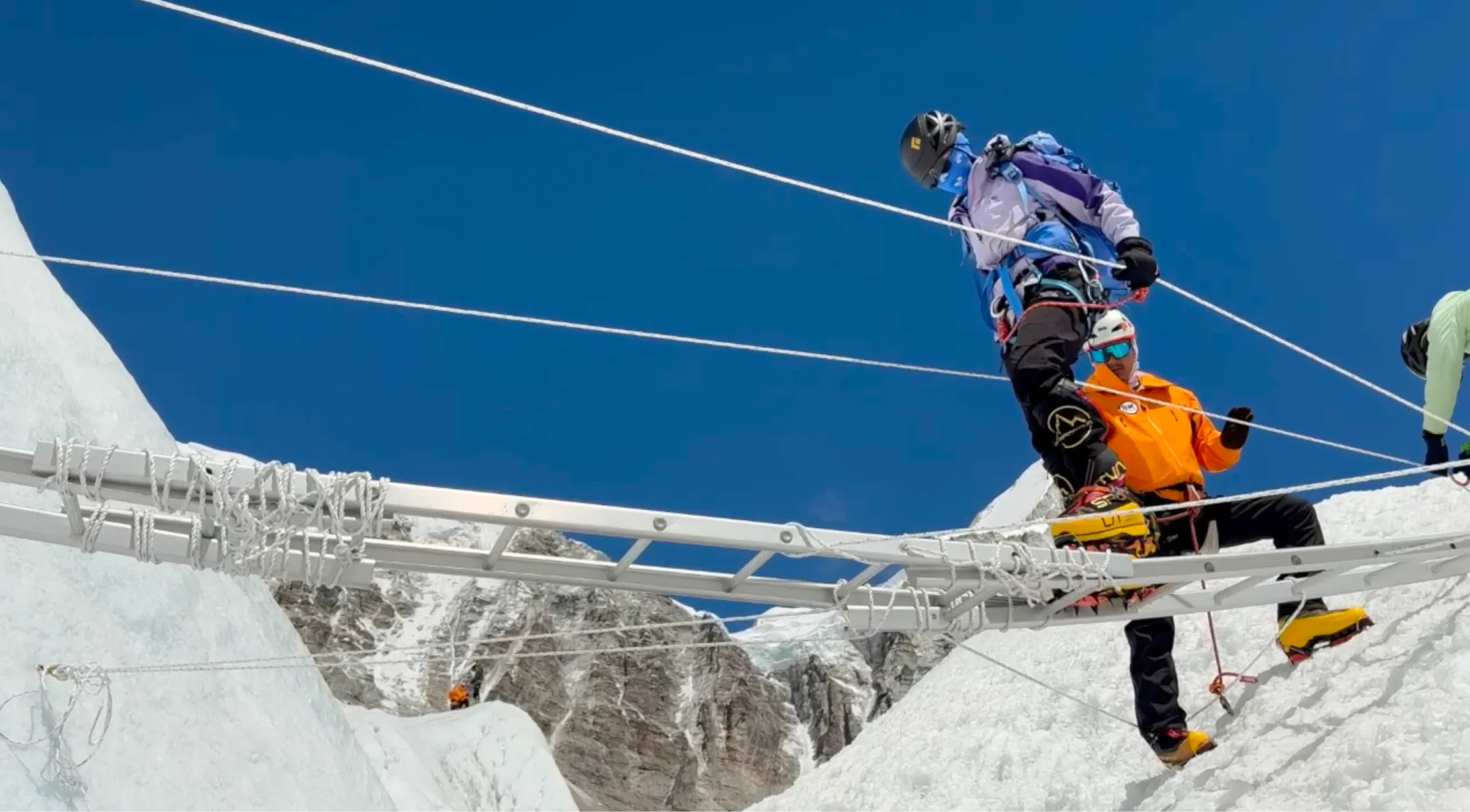 Climbers crossing a ladder over a crevasse in the Khumbu Icefall